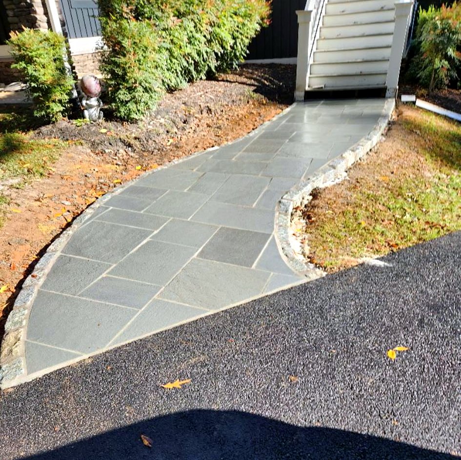 Curved bluestone walkway with cobblestone edging leading to a front entry