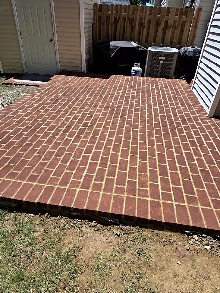 Finished red brick paver patio laid in running bond beside a home