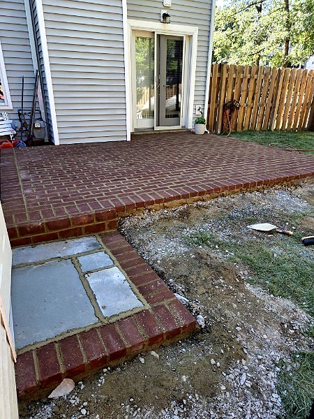 Raised brick paver patio with a soldier course edge, step, and flagstone landing