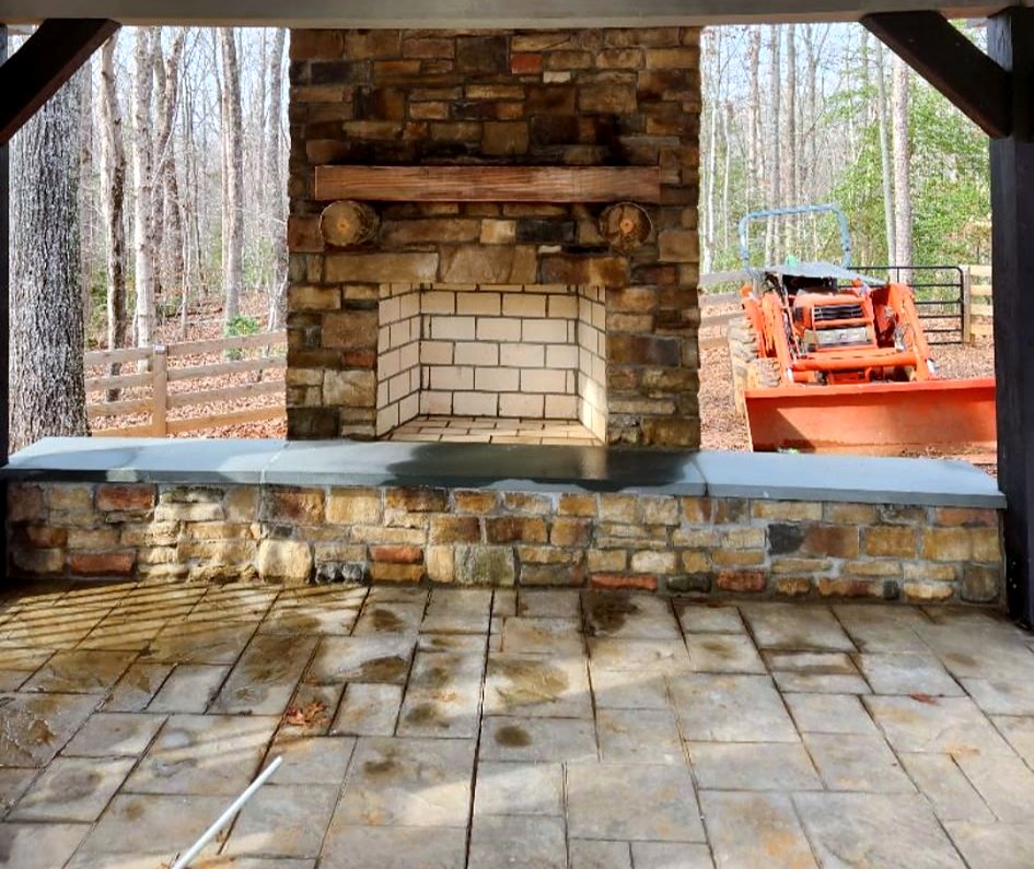 Stone outdoor fireplace with timber mantel inside a covered pavilion