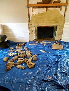 Interior fireplace stripped back before stone veneer, with stone laid out on a tarp