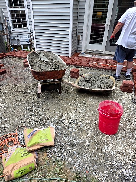 Wheelbarrows of fresh mortar on a job site during a brick patio installation