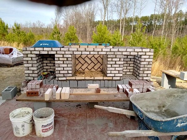 Brick outdoor fireplace under construction showing block core and herringbone firebox