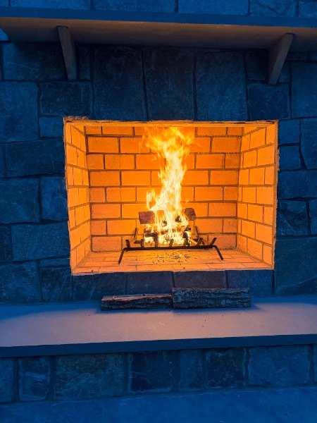 Close view of a firebrick firebox with fire burning in a stone outdoor fireplace