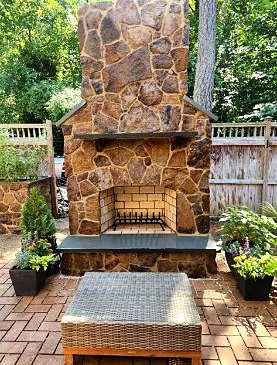Fieldstone outdoor fireplace with bluestone hearth on a brick paver patio